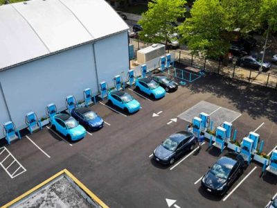 A building and 7 black and blue cars outside the building on road